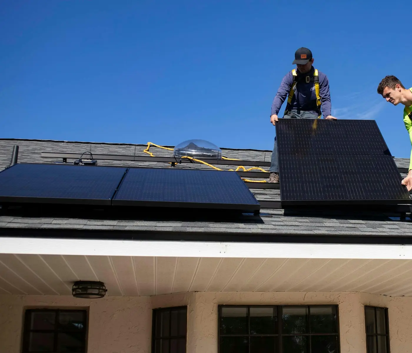 Two installers fitting solar panels to a roof.