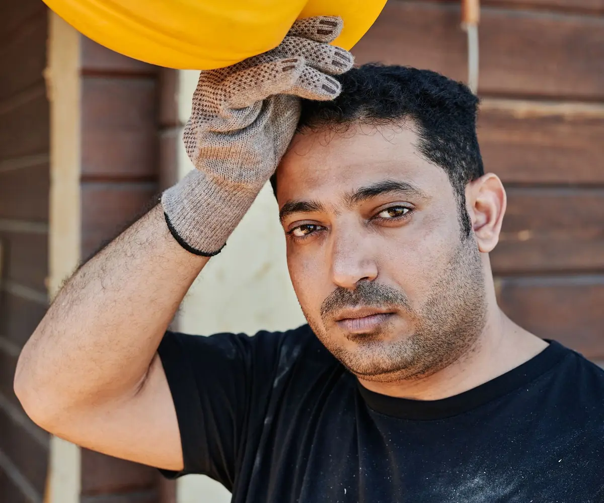 A site worker pausing with his hard hat in his hand.