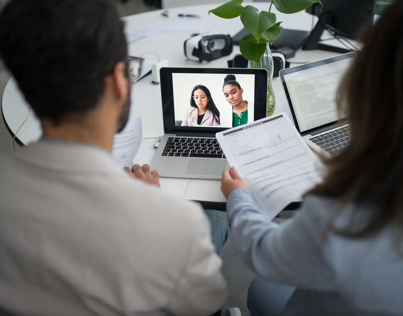 Two colleagues running an interview over a video call from a shared desk.